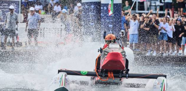 A participant speeds through water on an electric speed boat during the Monaco Energy Boat Challenge as spectators watch from the shore.