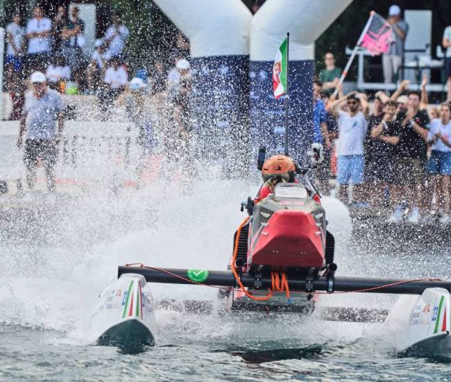 A participant speeds through water on an electric speed boat during the Monaco Energy Boat Challenge as spectators watch from the shore.